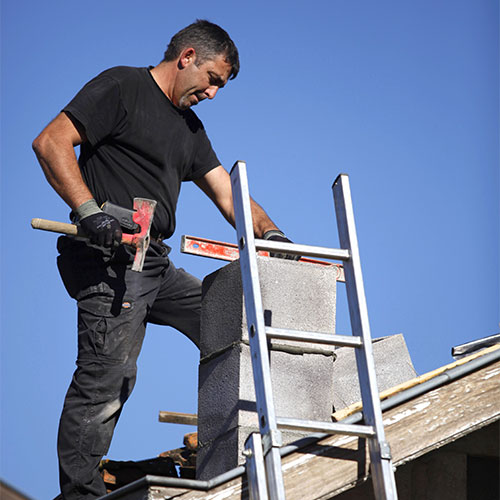 Chimney technician completing repairs on a roof with a ladder leaning against it