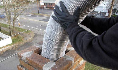 close up of technicians's hands feeding new chimney liner through top of chimney