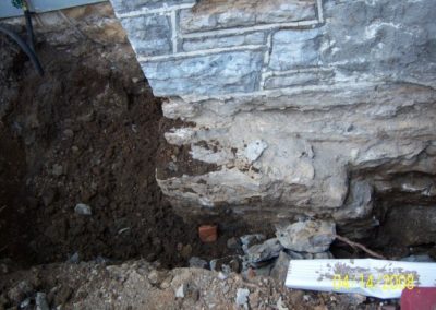 Chimney Foundation repair in progress showing dirt dug up around foundation damage