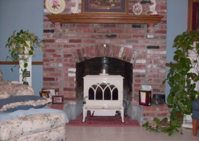 Completed Fireplace Installation with white stove insert sitting atop red masonry