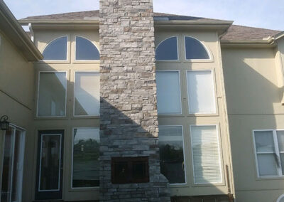 Outside of beige house with a stone chimney