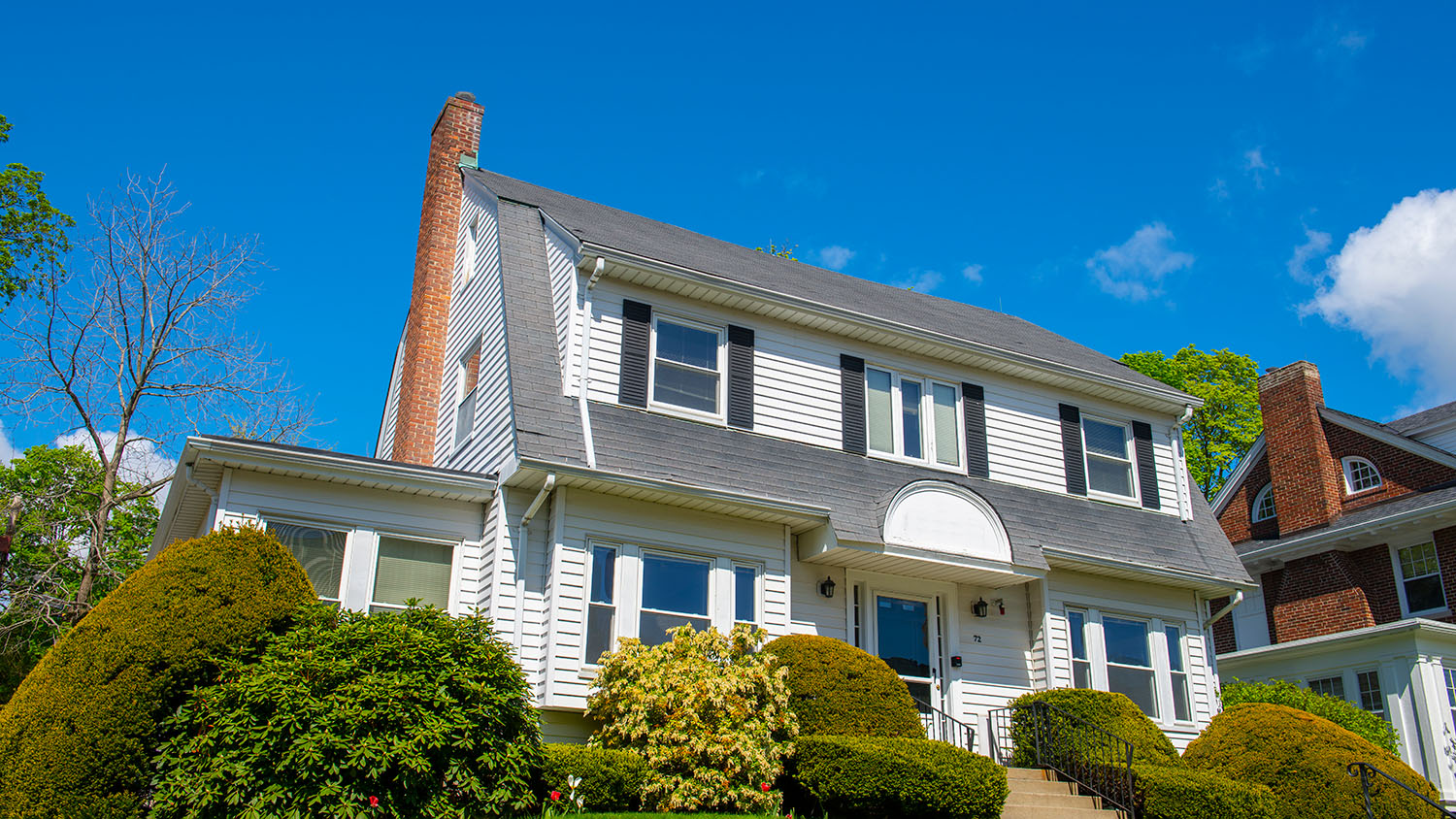 Sleep Easy-Stock of home white suburban home white blue shutters and a red brick chimney